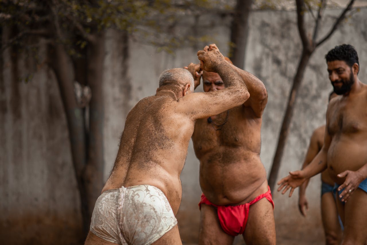 Men engage in a traditional wrestling match outdoors in Sialkot, showcasing cultural sportsmanship.