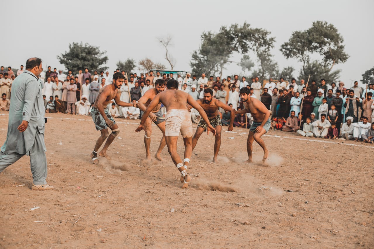 Men engage in a traditional Kabaddi match in Sillanwali, Pakistan with a large crowd watching.